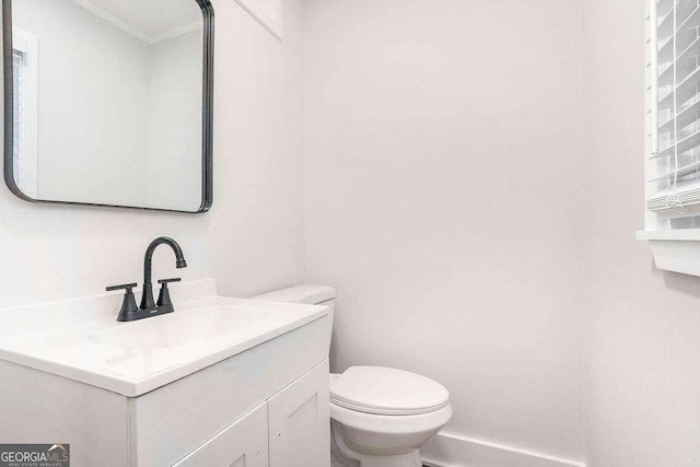 bathroom featuring vanity, toilet, and ornamental molding