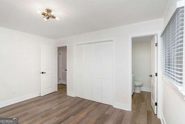 unfurnished bedroom with wood finished floors, a closet, ornamental molding, and baseboards