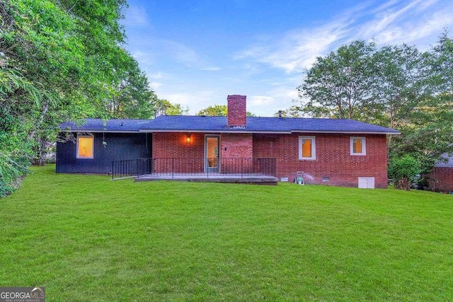 back of property with a lawn, brick siding, and a chimney