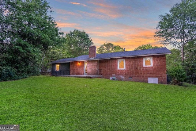 back of house with a yard, crawl space, a chimney, and brick siding