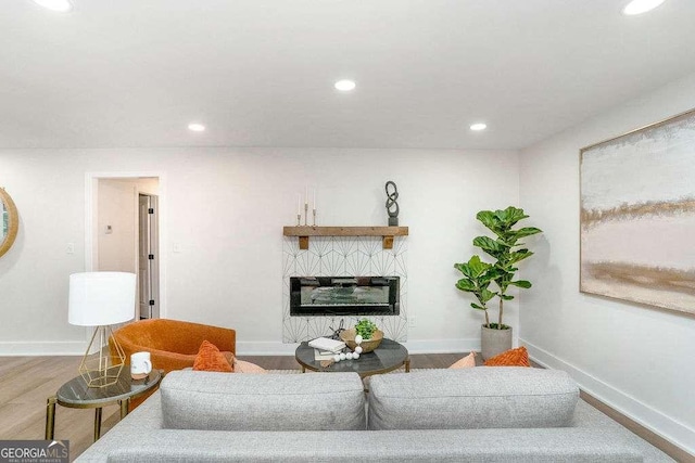living area featuring recessed lighting, baseboards, a glass covered fireplace, and wood finished floors