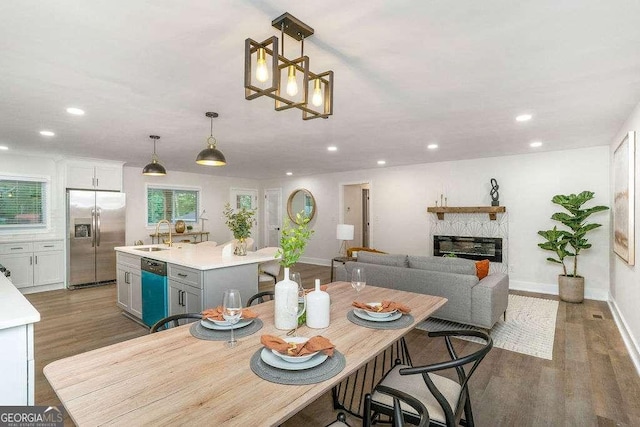 dining area with light wood finished floors, recessed lighting, baseboards, and a glass covered fireplace
