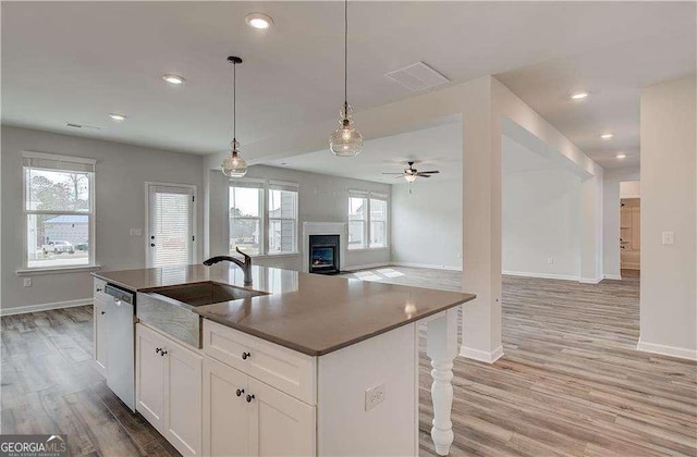 242 Linford Dr, Locust Grove, GA 30248 - kitchen featuring stainless steel dishwasher, ceiling fan, open floor plan, light wood finished floors, and a warm lit fireplace