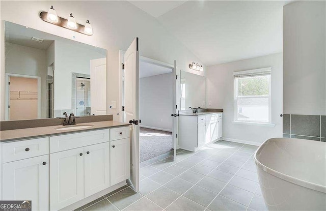 242 Linford Dr, Locust Grove, GA 30248 - bathroom with tile patterned floors, two vanities, lofted ceiling, a stall shower, and a soaking tub