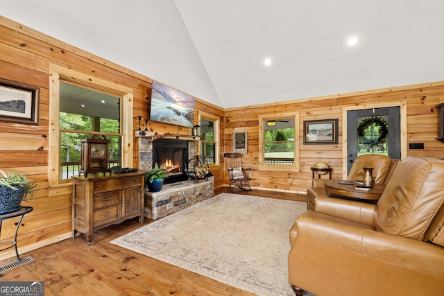 living room with wooden walls, high vaulted ceiling, wood-type flooring, a fireplace, and recessed lighting
