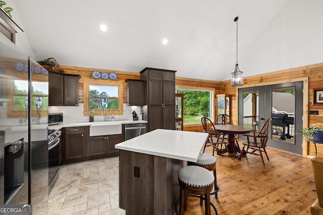 kitchen with a sink, high vaulted ceiling, french doors, plenty of natural light, and light countertops
