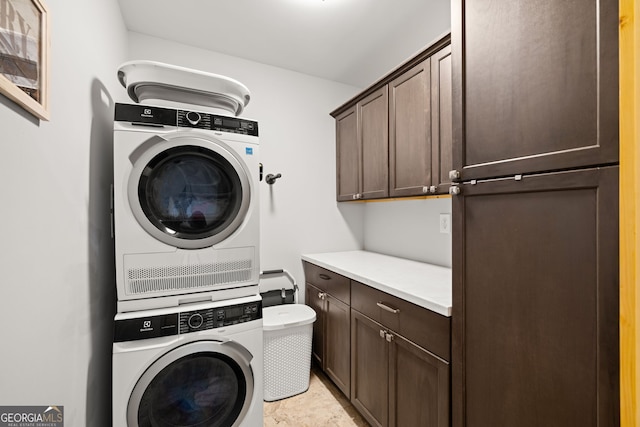 laundry room featuring stacked washer and clothes dryer and cabinet space