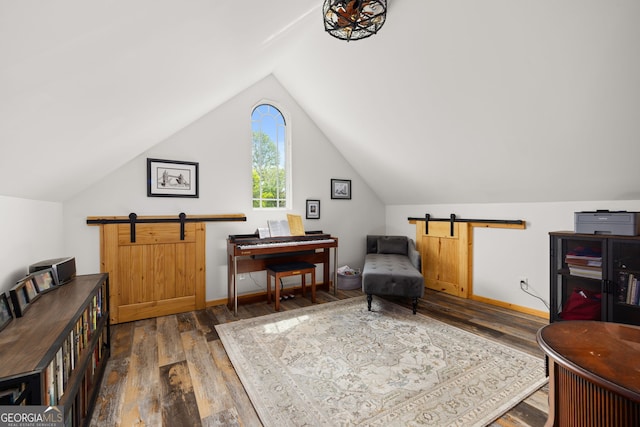 living area with a barn door, wood finished floors, and vaulted ceiling