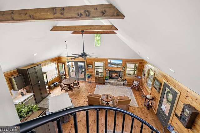 living area featuring wood walls, beamed ceiling, hardwood / wood-style flooring, high vaulted ceiling, and a fireplace