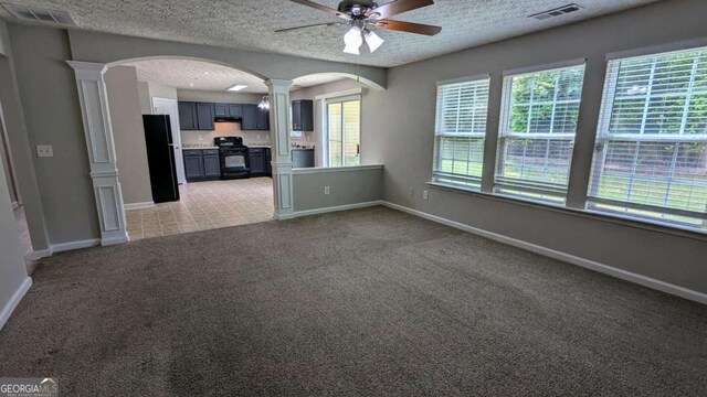 2153 Pine View Trl, Ellenwood, GA 30294 - unfurnished living room with ornate columns, a ceiling fan, arched walkways, light colored carpet, and a textured ceiling