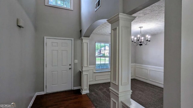 2153 Pine View Trl, Ellenwood, GA 30294 - foyer featuring ornate columns, arched walkways, dark carpet, a wainscoted wall, and a chandelier
