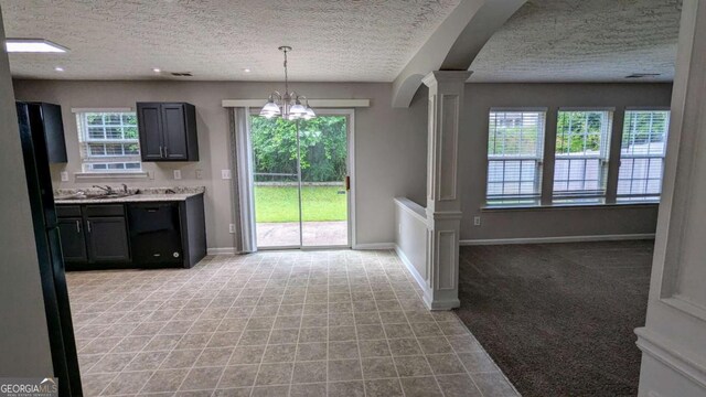 2153 Pine View Trl, Ellenwood, GA 30294 - unfurnished dining area with ornate columns, a textured ceiling, a chandelier, baseboards, and light colored carpet