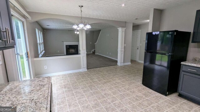 2153 Pine View Trl, Ellenwood, GA 30294 - kitchen with freestanding refrigerator, a textured ceiling, arched walkways, ornate columns, and a glass covered fireplace
