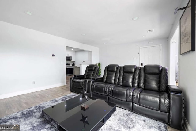 cinema featuring wood finished floors, recessed lighting, and baseboards