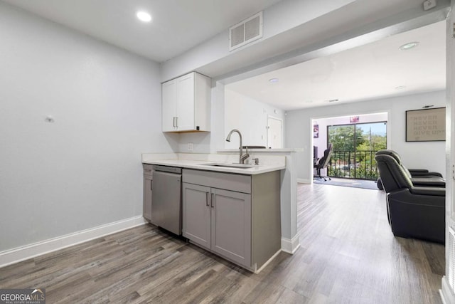 kitchen with a sink, stainless steel dishwasher, open floor plan, light countertops, and baseboards
