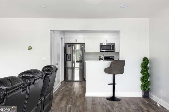 kitchen featuring stainless steel appliances, open floor plan, dark wood-type flooring, a breakfast bar, and baseboards