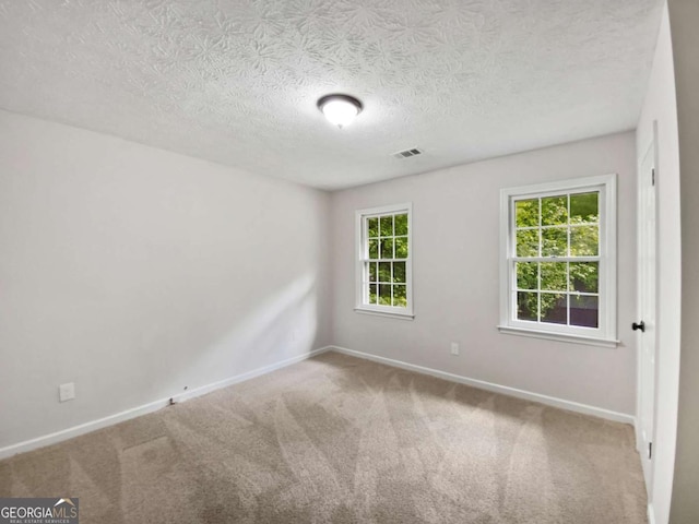 carpeted empty room with baseboards and a textured ceiling