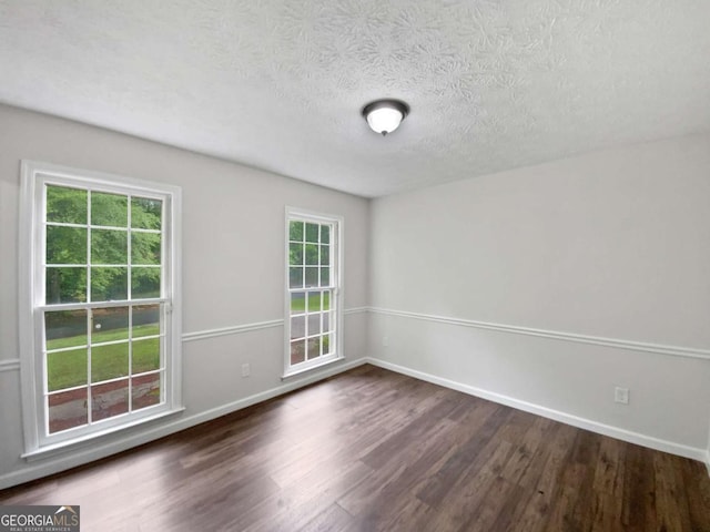 spare room with wood finished floors, baseboards, and a textured ceiling