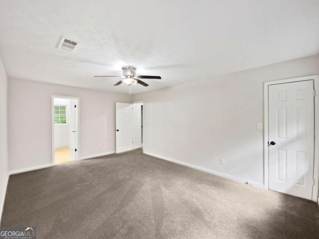 carpeted spare room with a ceiling fan and baseboards