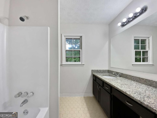 full bath featuring vanity, a textured ceiling, bathing tub / shower combination, baseboards, and tile patterned flooring