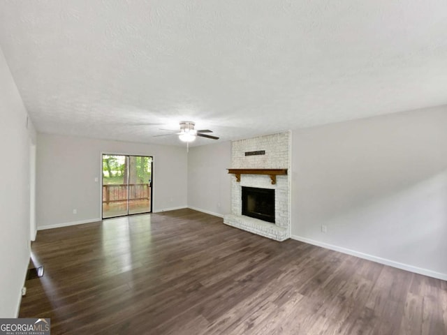 unfurnished living room with ceiling fan, dark wood-style floors, baseboards, and a brick fireplace