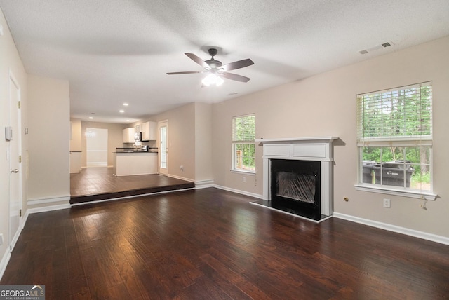 4615 Thermal Ct, Douglasville, GA 30135 - unfurnished living room featuring dark wood-type flooring, a ceiling fan, a glass covered fireplace, and baseboards