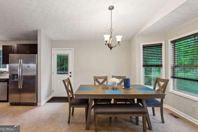 dining area featuring a chandelier, baseboards, a textured ceiling, and light tile patterned floors