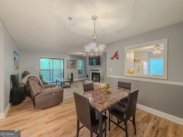 2610 Cumberland Ct, Smyrna, GA 30080 - dining room with light wood finished floors, a chandelier, a textured ceiling, a glass covered fireplace, and baseboards