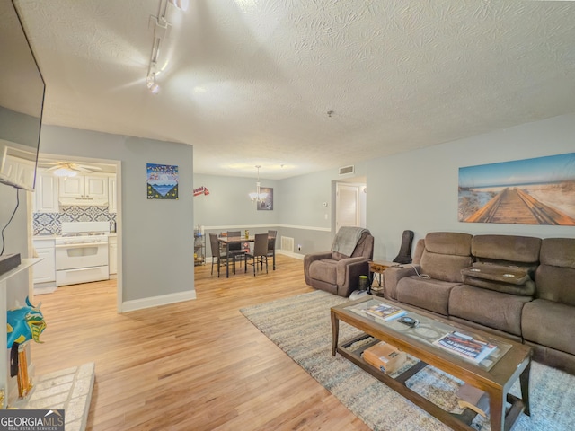 2610 Cumberland Ct, Smyrna, GA 30080 - living area with light wood-type flooring, a chandelier, rail lighting, baseboards, and a textured ceiling