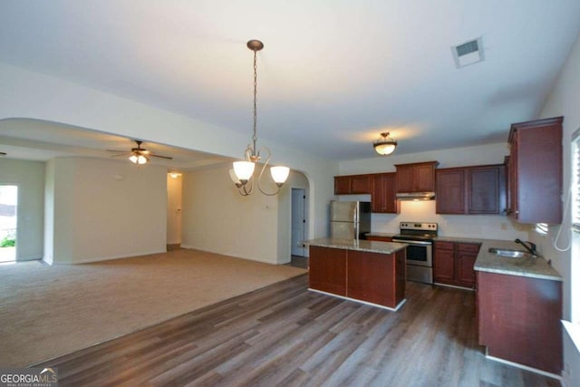 kitchen with stainless steel appliances, a sink, ceiling fan, arched walkways, and a kitchen island