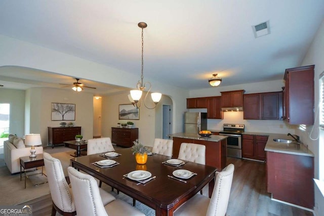 dining room with arched walkways, a ceiling fan, and dark wood-style flooring