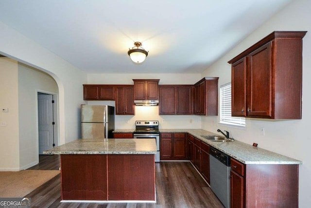 kitchen featuring stainless steel appliances, a sink, under cabinet range hood, dark wood-style floors, and a kitchen island