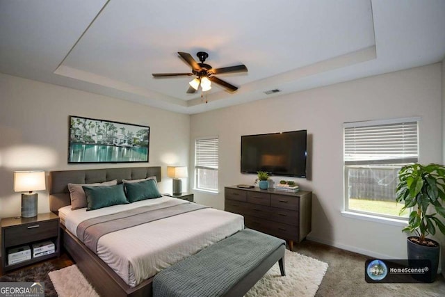 bedroom featuring a raised ceiling, baseboards, ceiling fan, and carpet flooring