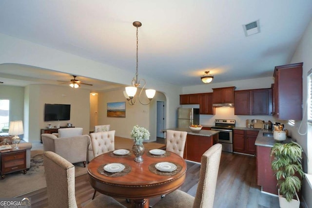 dining room with arched walkways, a ceiling fan, and dark wood-style floors