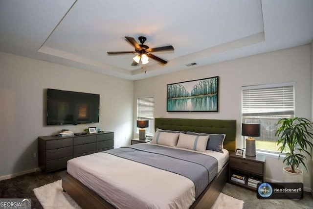 bedroom with a raised ceiling, carpet, baseboards, and a ceiling fan