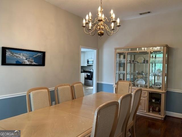 1009 Hunters Pointe Dr, Statesboro, GA 30461 - dining room with a chandelier, dark wood-style floors, and baseboards