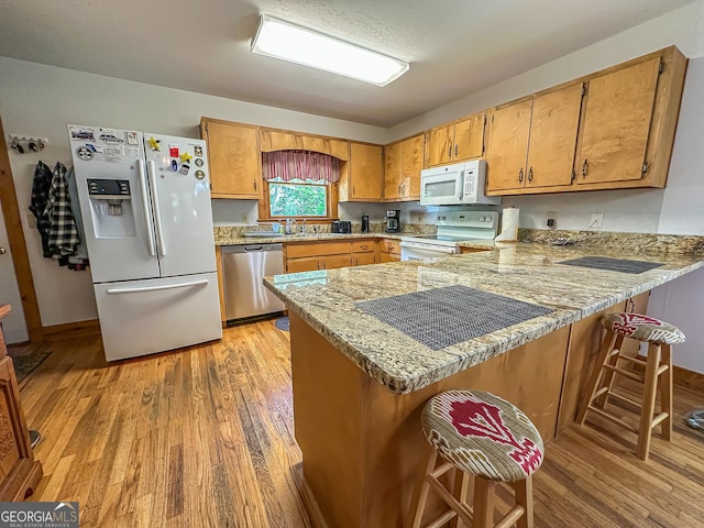 30 Putter Ln, Dillard, GA 30537 - kitchen featuring white appliances, light wood-style flooring, a peninsula, a sink, and a breakfast bar area