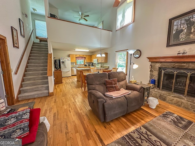 30 Putter Ln, Dillard, GA 30537 - living area featuring ceiling fan, light wood-style flooring, a high ceiling, stairs, and a stone fireplace