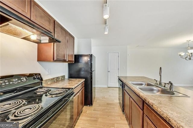 kitchen with black appliances, a sink, under cabinet range hood, light wood-style floors, and a chandelier