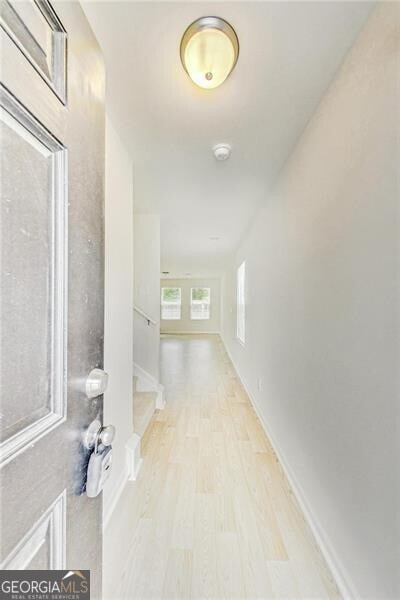 hall featuring baseboards and light wood-style flooring