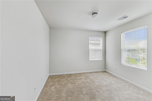 empty room featuring healthy amount of natural light, carpet flooring, and baseboards