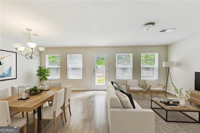 living area with healthy amount of natural light, a chandelier, light wood-style flooring, and baseboards