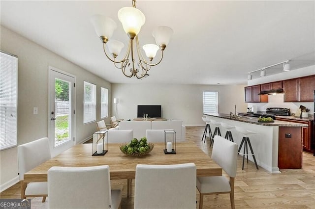 dining room featuring a chandelier, track lighting, light wood-type flooring, and baseboards