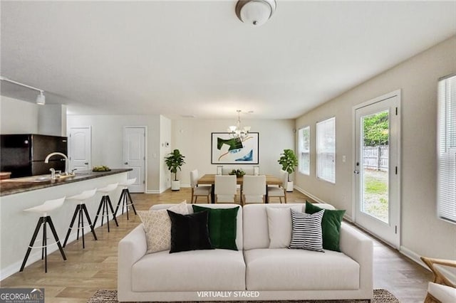 living room featuring a chandelier, baseboards, and light wood finished floors