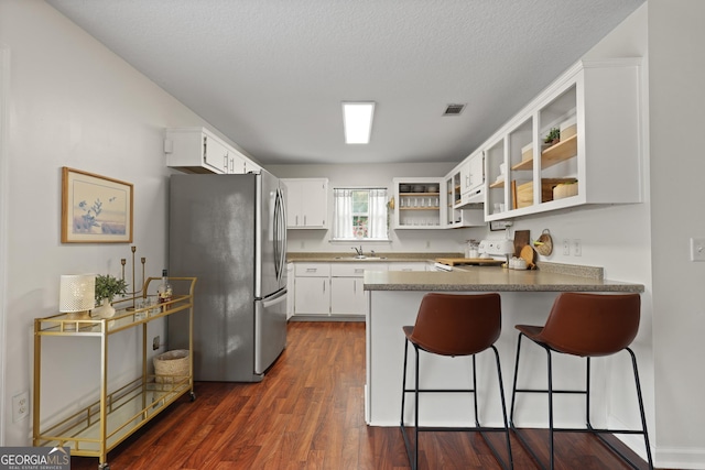 142 Dawn Cir, Brunswick, GA 31523 - kitchen with freestanding refrigerator, a peninsula, a sink, stove, and dark wood-style floors