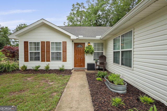 142 Dawn Cir, Brunswick, GA 31523 - view of exterior entry featuring roof with shingles, central air condition unit, and a yard