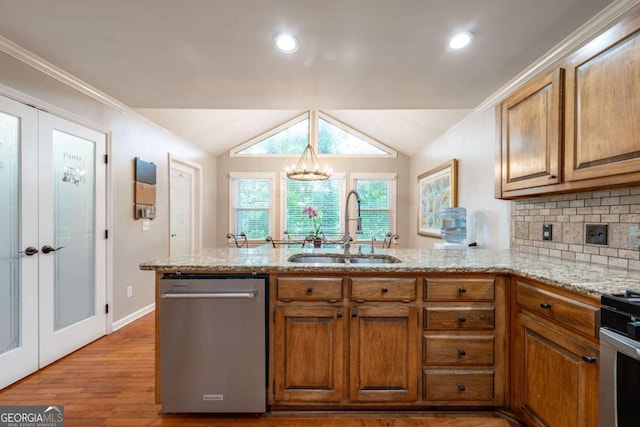 kitchen featuring appliances with stainless steel finishes, a sink, brown cabinets, a peninsula, and wood finished floors