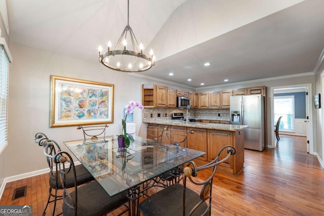 dining room with a chandelier, light wood-style flooring, baseboards, ornamental molding, and recessed lighting