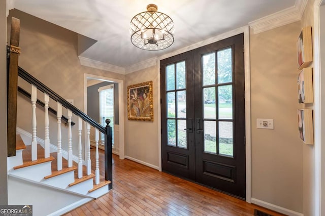 foyer featuring french doors, baseboards, hardwood / wood-style flooring, stairs, and crown molding