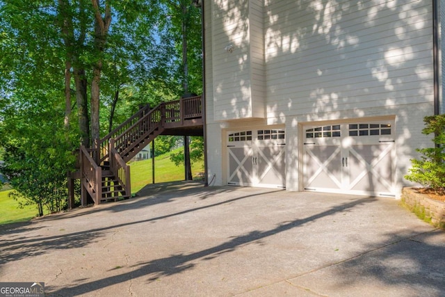 view of side of home with driveway, a garage, stairs, and a wooden deck